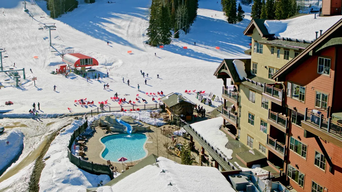 A vibrant scene showing the pool area with people relaxing, ski slopes and lifts in the background, and the hotel building nestled in a snowy landscape. The image conveys both energetic winter activity and the inviting amenities awaiting guests after their outdoor adventures.