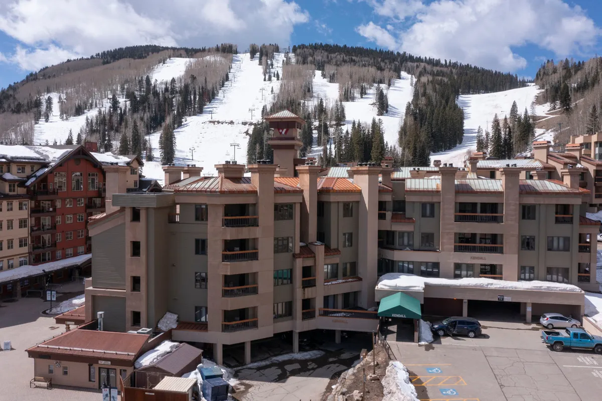 This image captures the building facade of the property set against a dramatic backdrop of snow-covered mountains and visible ski slopes. The scene evokes a sense of adventure and showcases Purgatory Resort's proximity to thrilling ski and snowboard opportunities, as well as the welcoming atmosphere of the lodge.