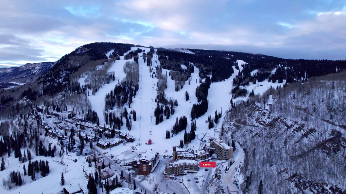 This image offers a sweeping view of ski slopes and snow-covered trees, with residential buildings and active ski lifts in the frame. The lively atmosphere illustrates the excitement and accessibility of outdoor mountain sports just outside the condo.